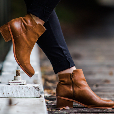 A woman stepping off a curb in her brown ankle boots